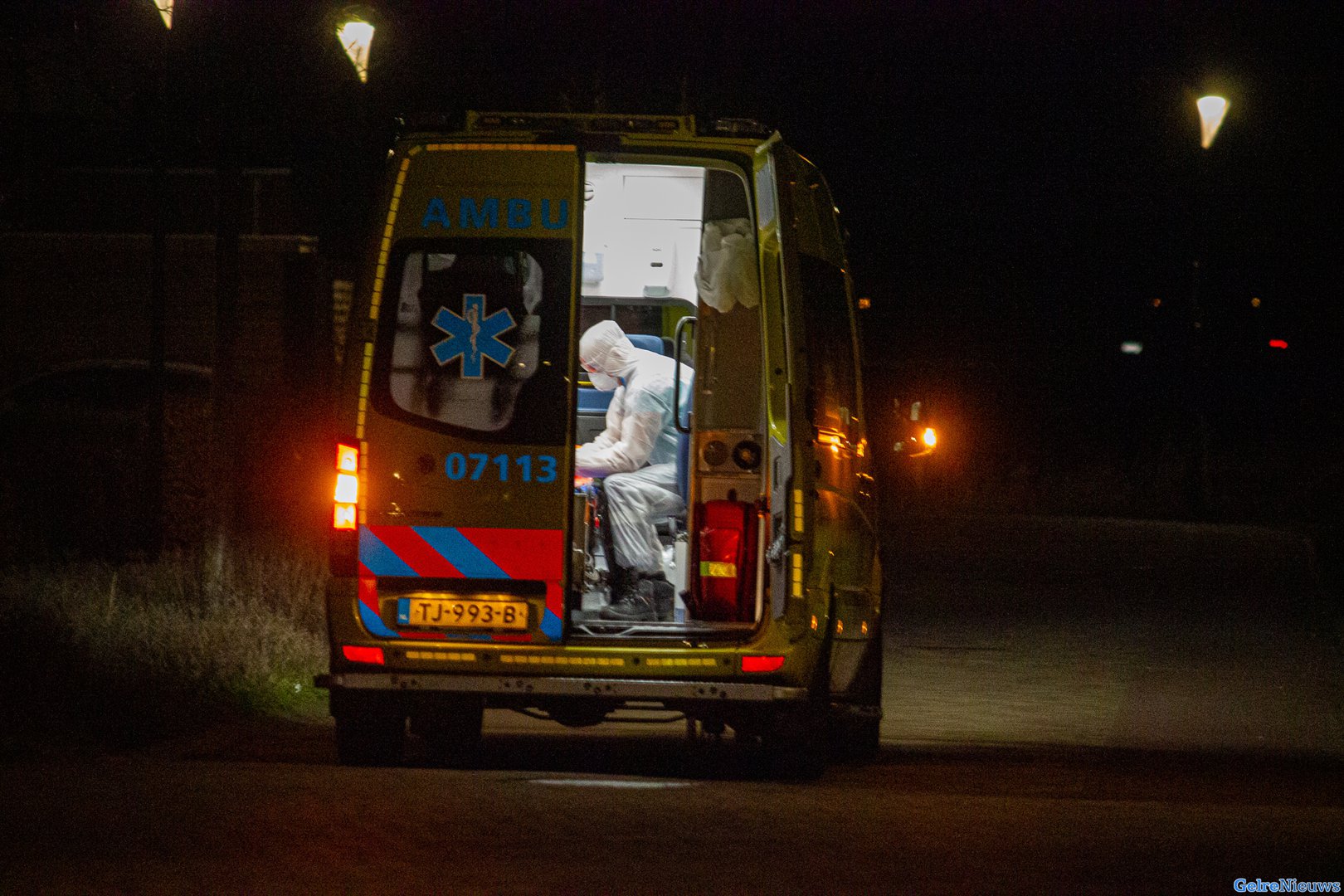 Ambulancepersoneel in beschermde kleding halen mogelijke coronapatiënten op