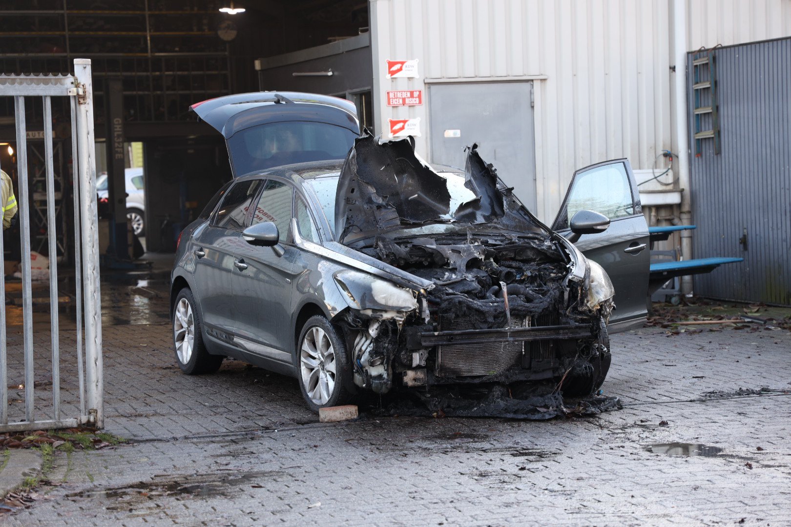 Hybride auto vat vlam in werkplaats in Arnhem-Zuid