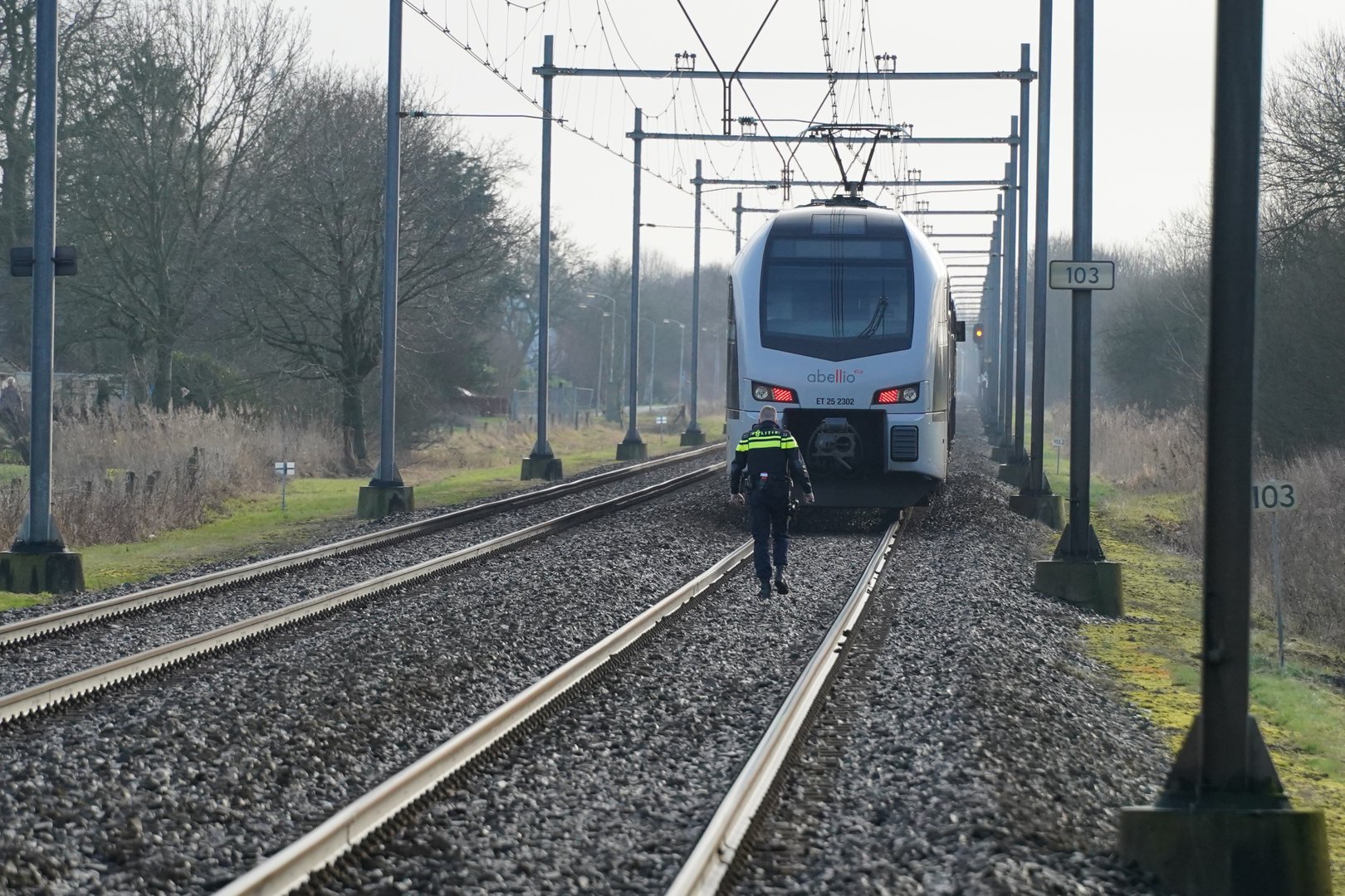 Verward persoon loopt over spoor en kan aanstormende trein net ontwijken