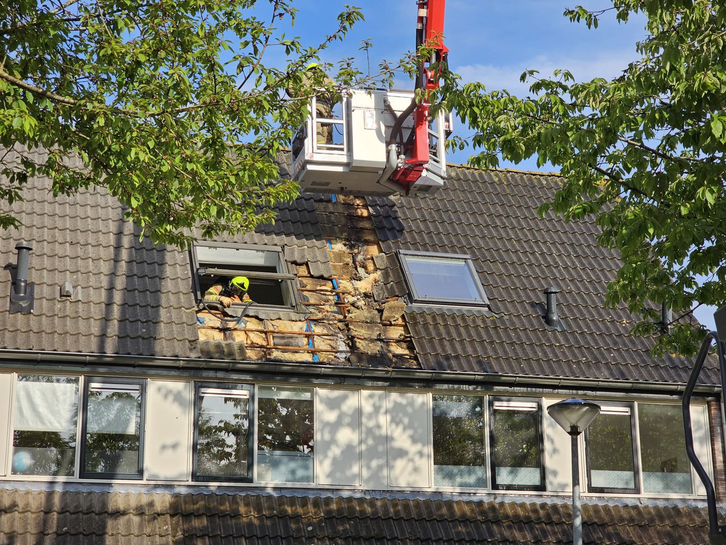 Brandweer verwijderd dakpannen om te kunnen blussen