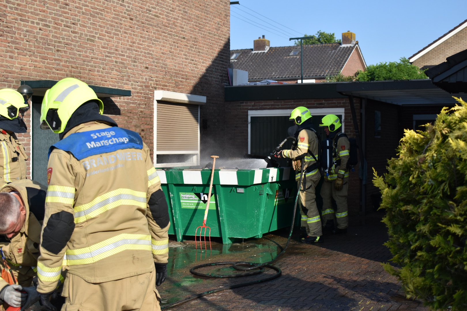 Vlammen slaan tegen woning bij containerbrand