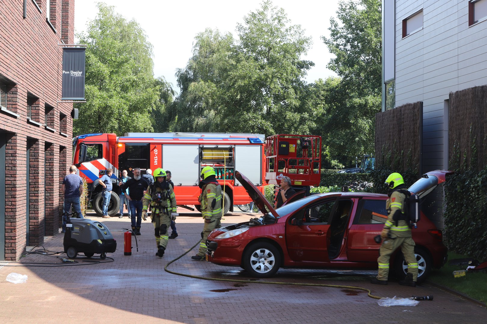 Omstanders duwen brandende auto uit pand