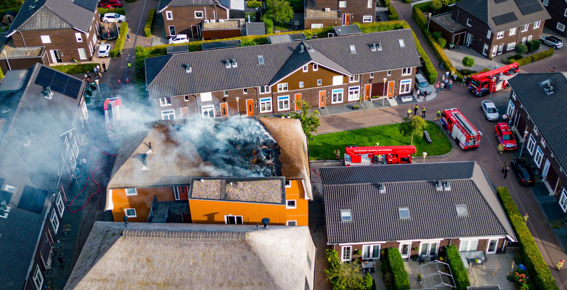 Grote rookwolken bij brand in rieten kap van appartementencomplex