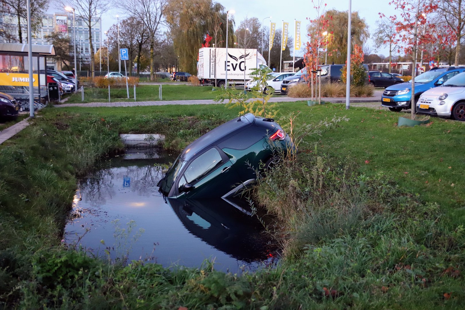 Geparkeerde auto rolt het water in bij winkelcentrum
