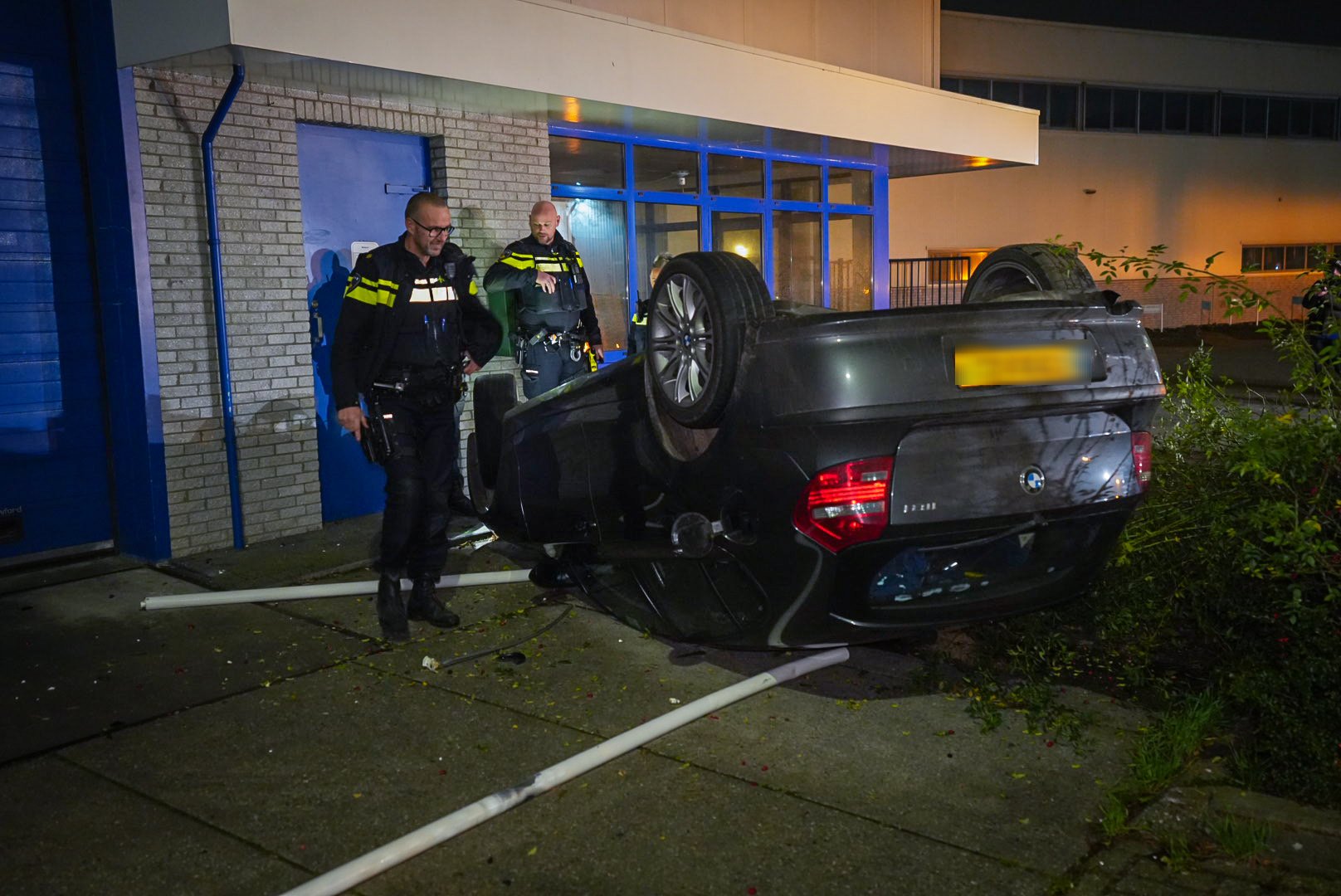 Auto op zijn dak voor een bedrijfspand na ongeval Duiven