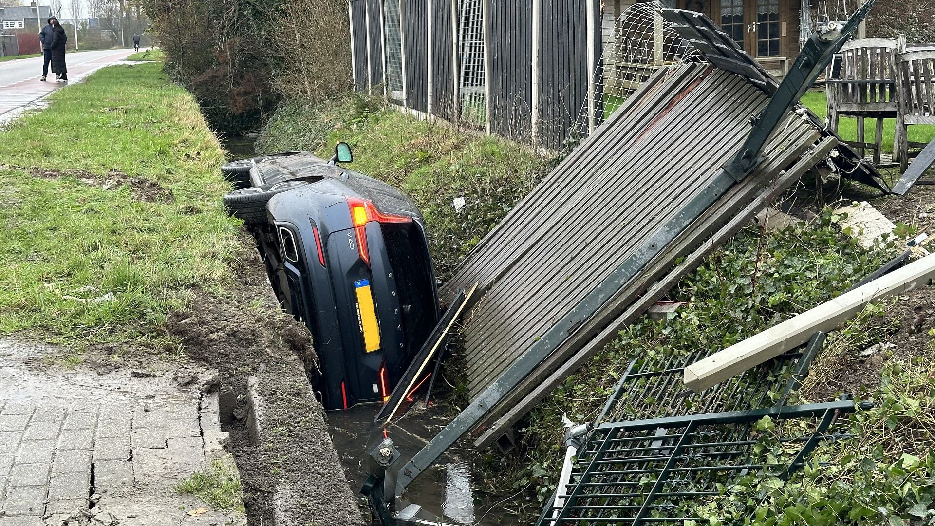 Auto belandt in sloot, brug en hekwerk gesneuveld