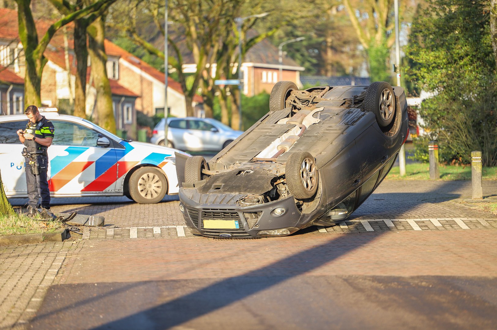 Auto over de kop in woonwijk door laagstaande zon