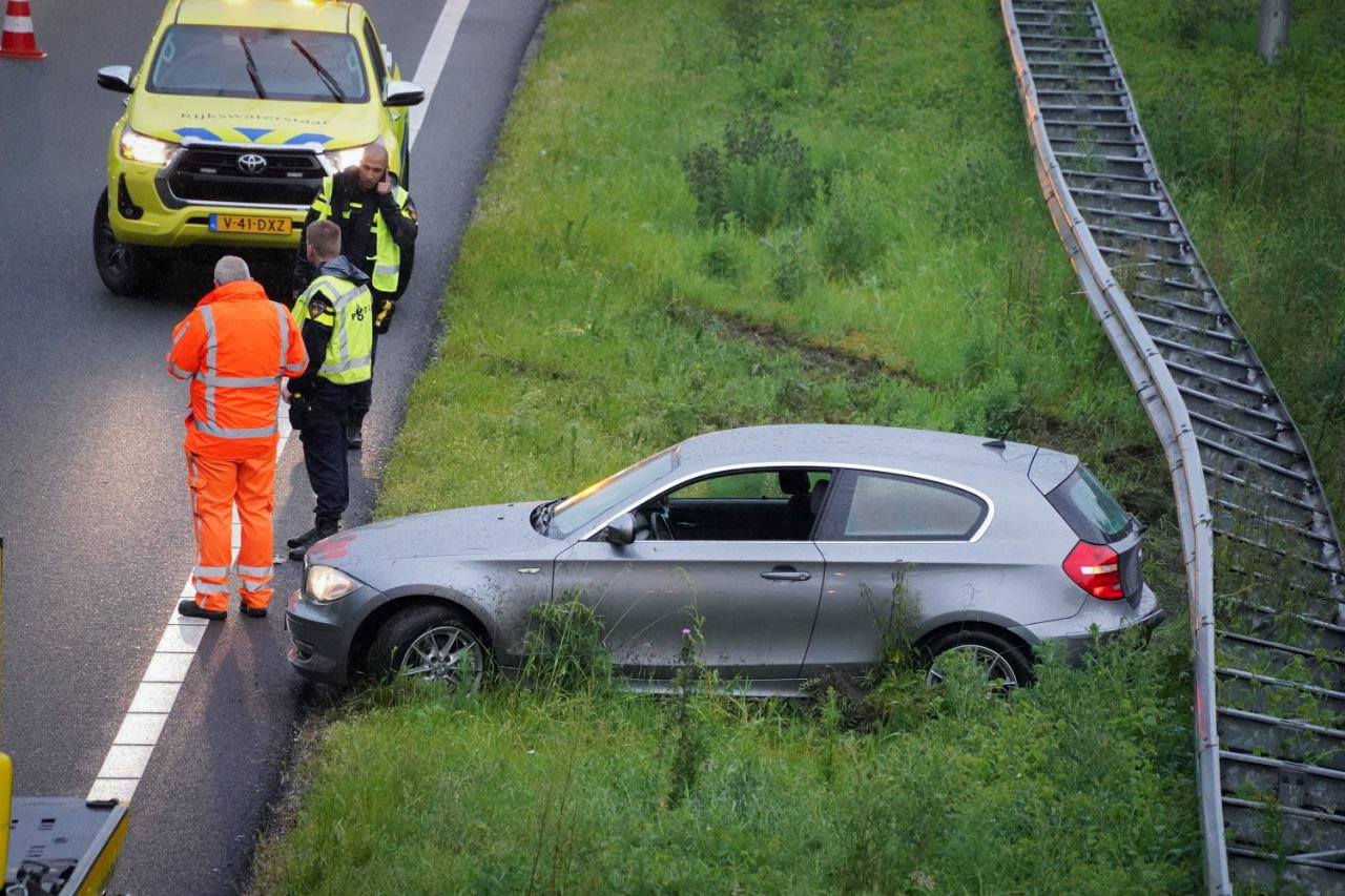 Auto raakt in de slip door ondergelopen snelweg en ramt vangrail