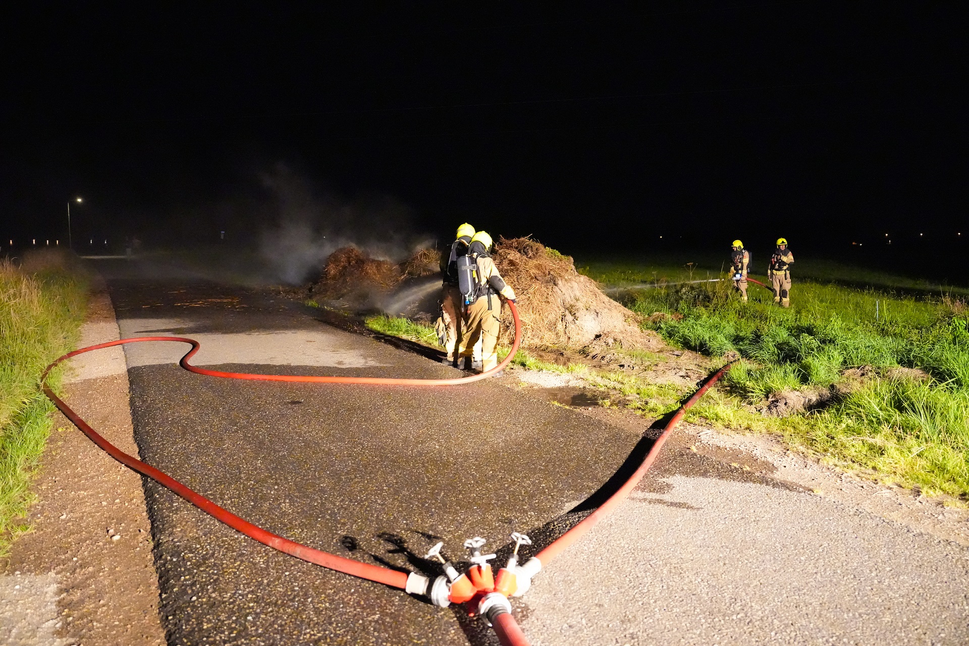Berg met riet vliegt in brand langs de weg
