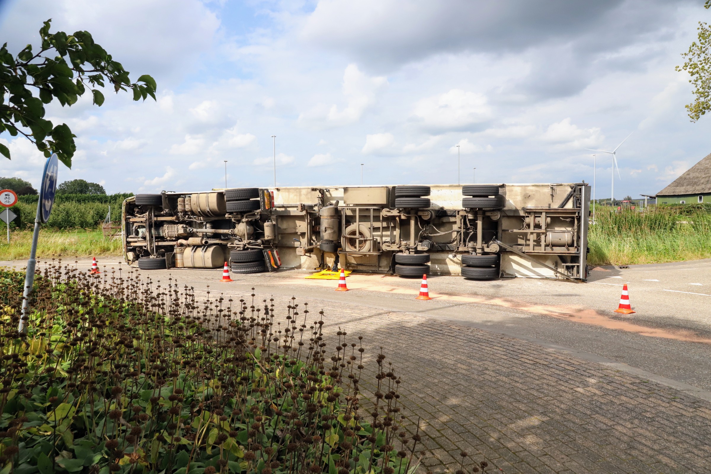 Vrachtwagen met appels kantelt op rotonde