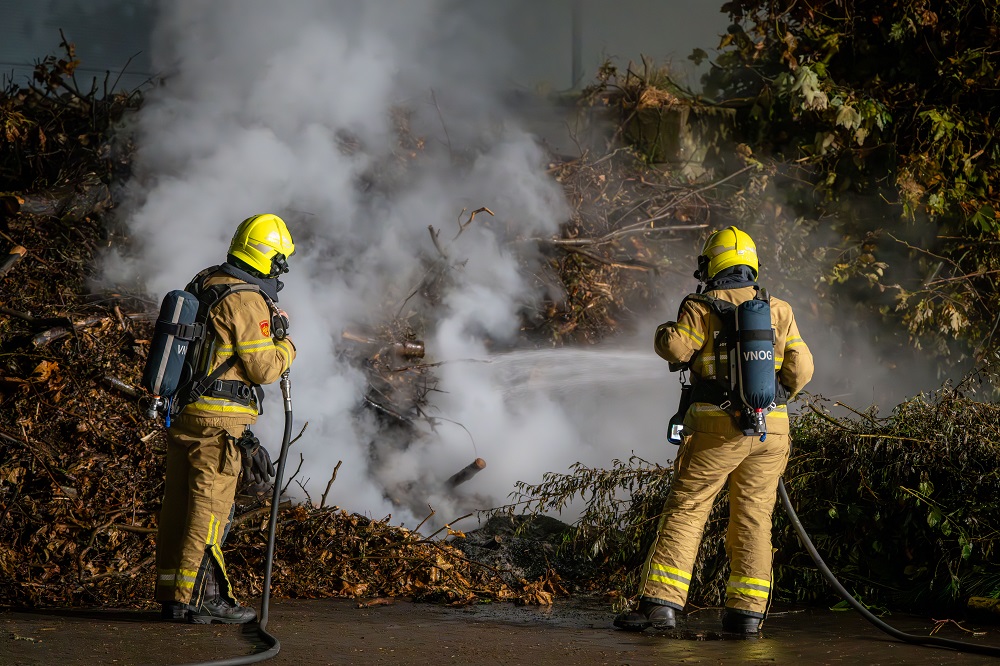 Grote berg met snoeiafval in brand op industrieterrein