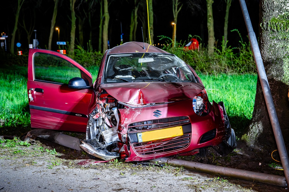 Auto vliegt uit de bocht en ramt lantaarnpaal en boom
