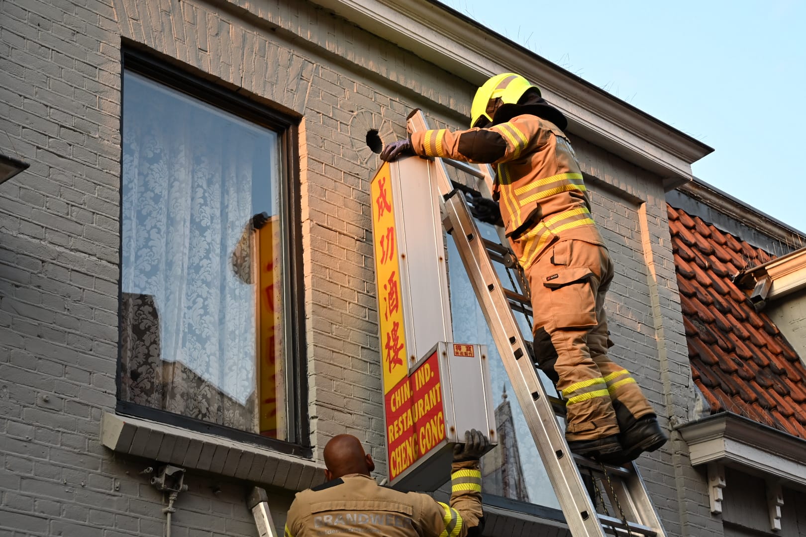 Brandweer haalt loshangend reclamebord naar beneden