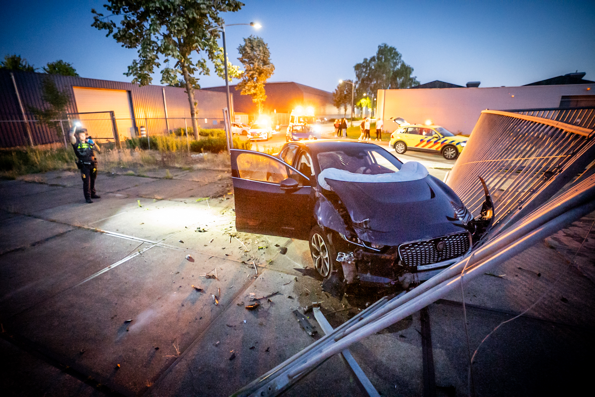 Jonge vrouw in Jaguar mist de bocht en rijdt poort uit de grond