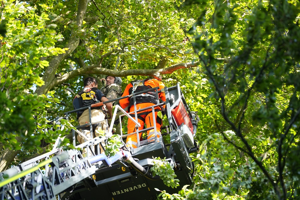 Parachutist landt hoog in de boom naast vliegveld