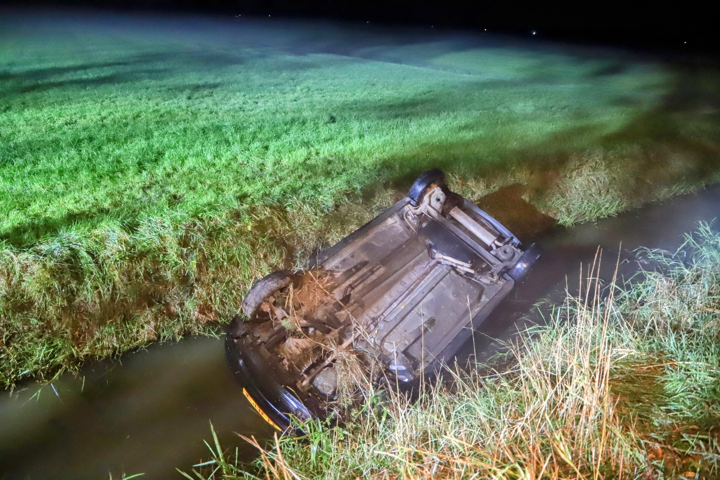 Auto op z’n kop in sloot, bestuurder met schrik vrij