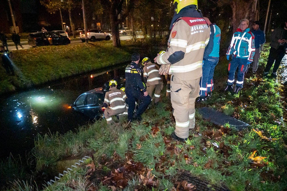 Auto te water, bestuurder door brandweer gered