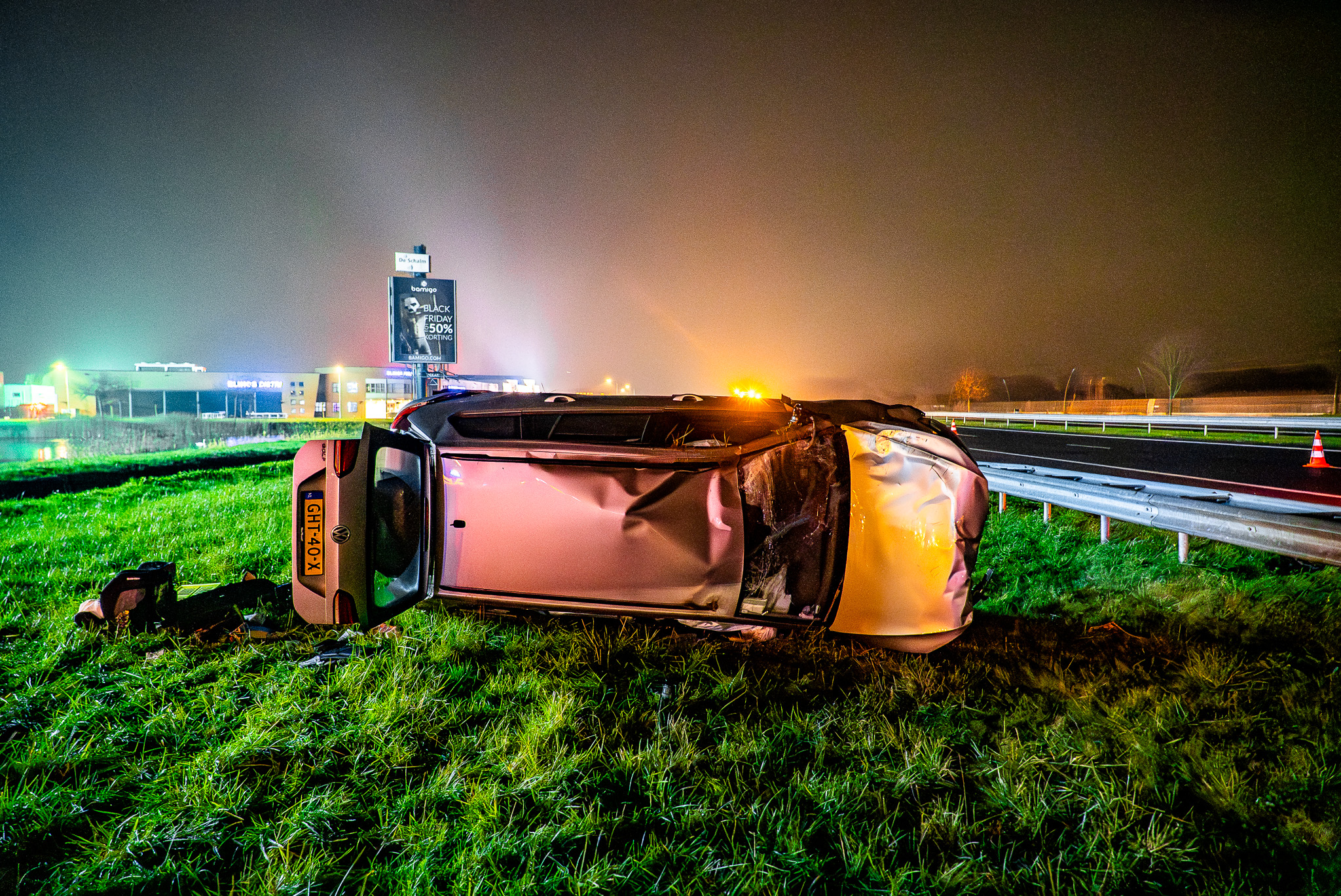 Auto op z’n kant langs snelweg, bestuurder gewond