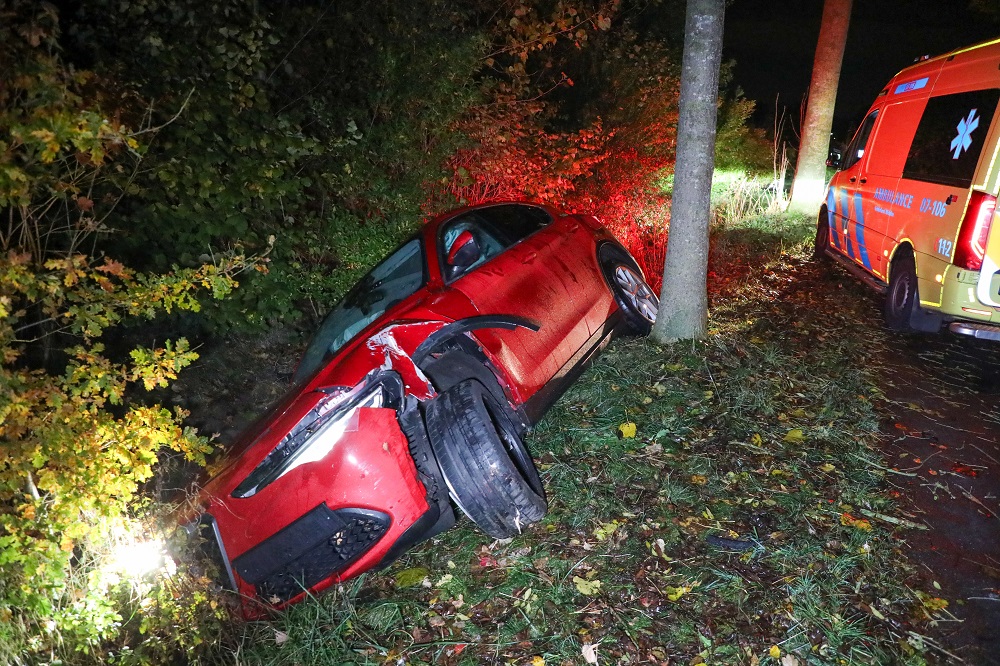 Auto in sloot na botsing tegen boom