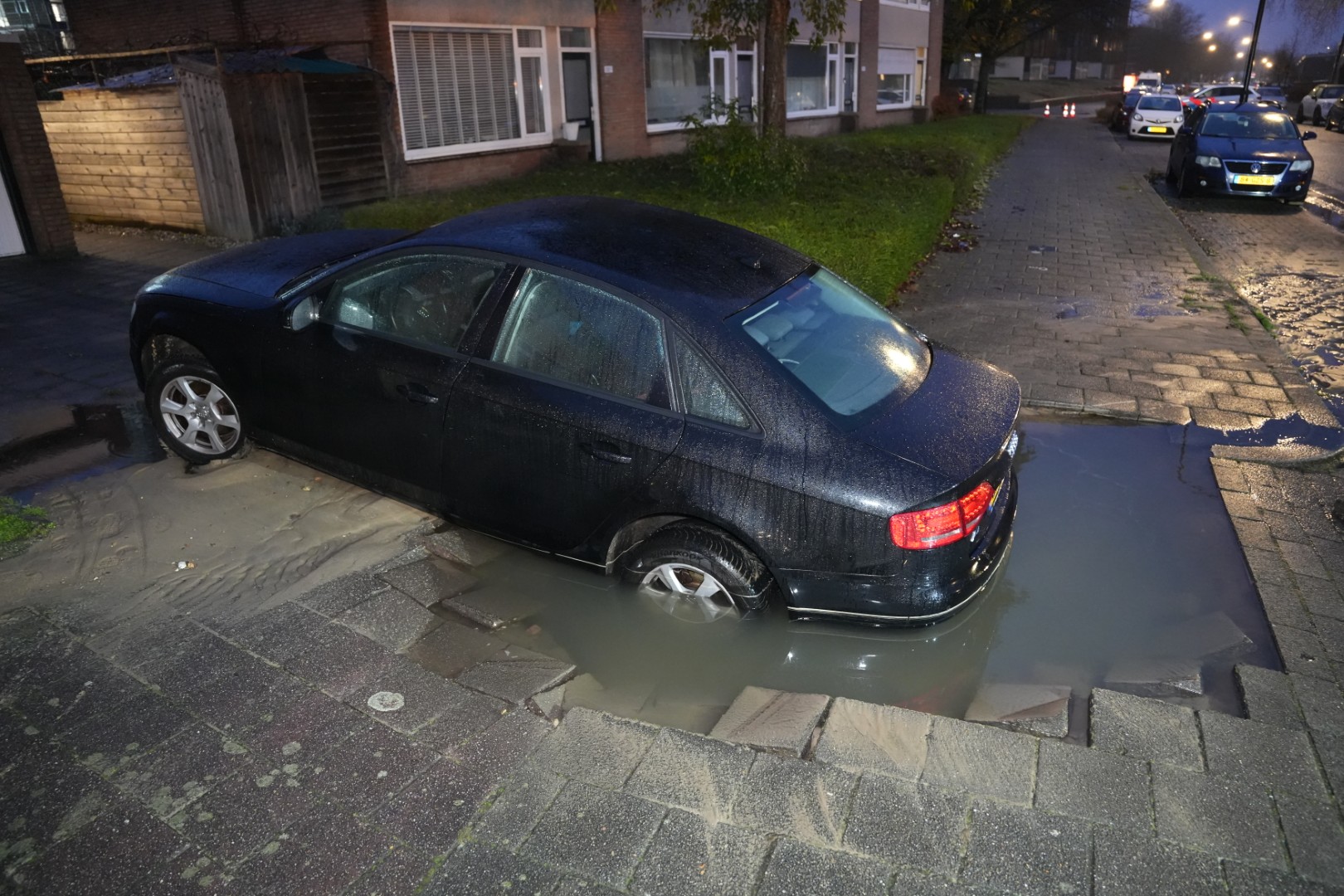 Auto zakt in sinkhole op een oprit bij een woning