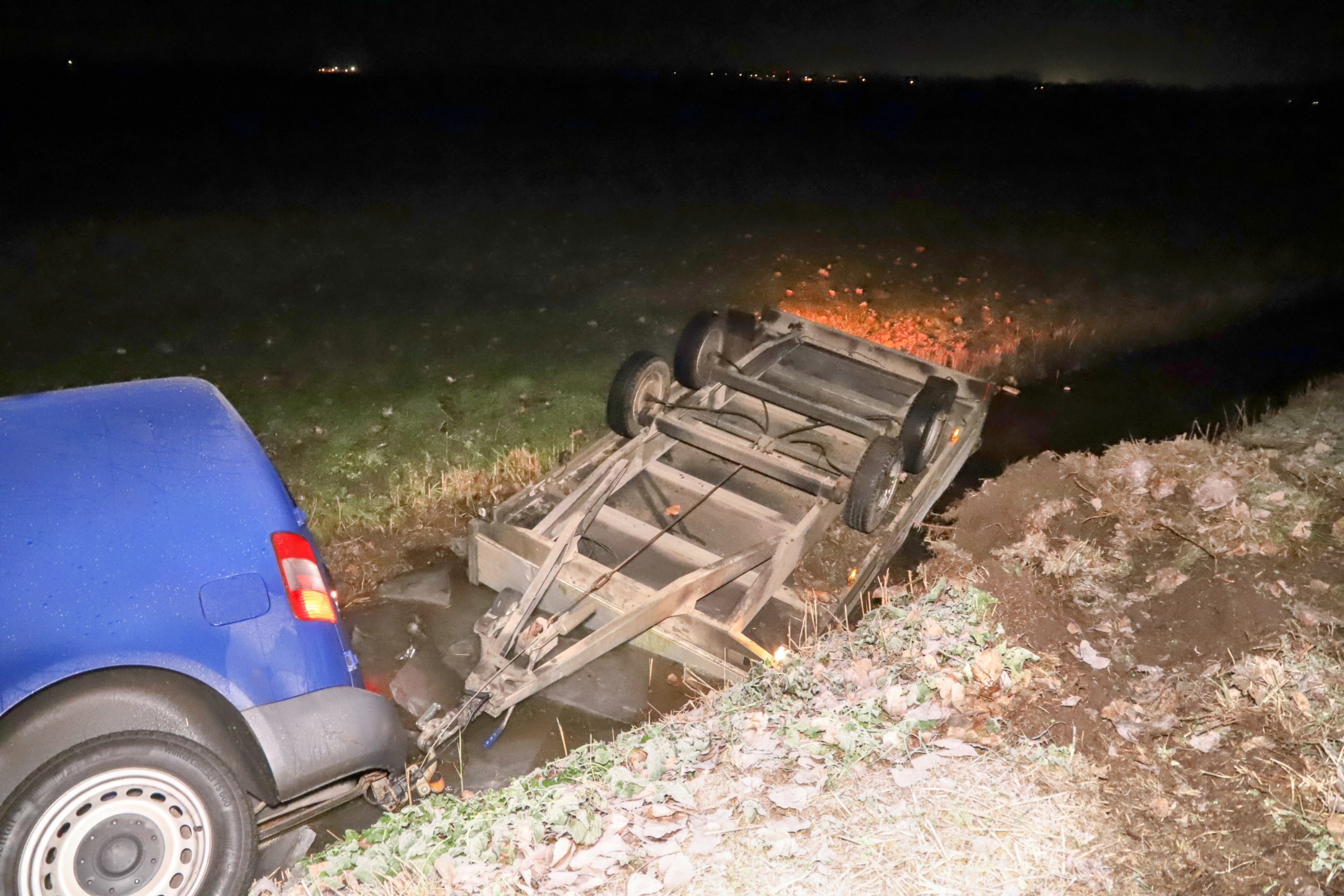 Bestelwagen met aanhanger in sloot door spekgladde weg