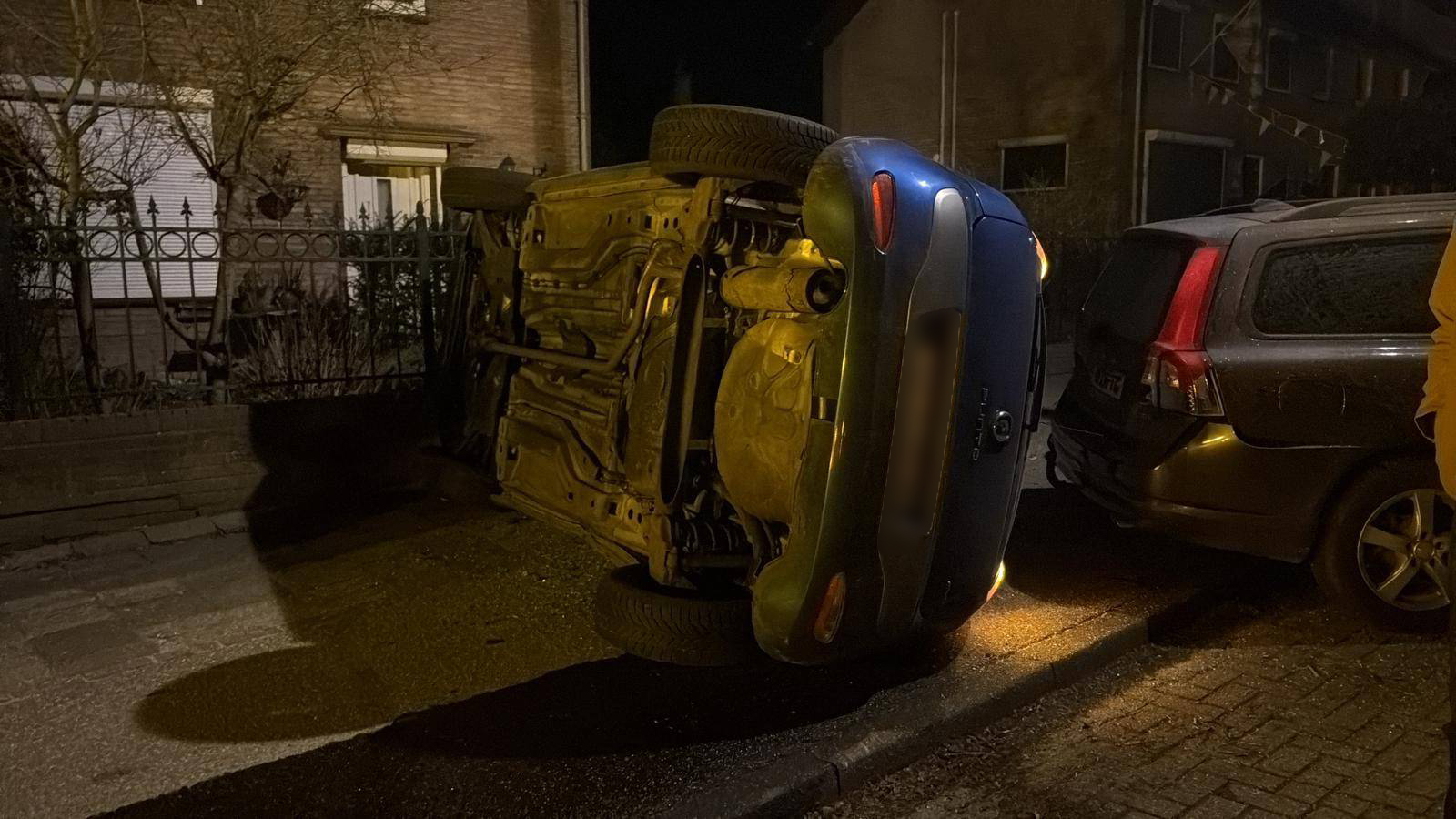 Auto belandt op zijkant tussen geparkeerde voertuigen, bestuurder naar ziekenhuis