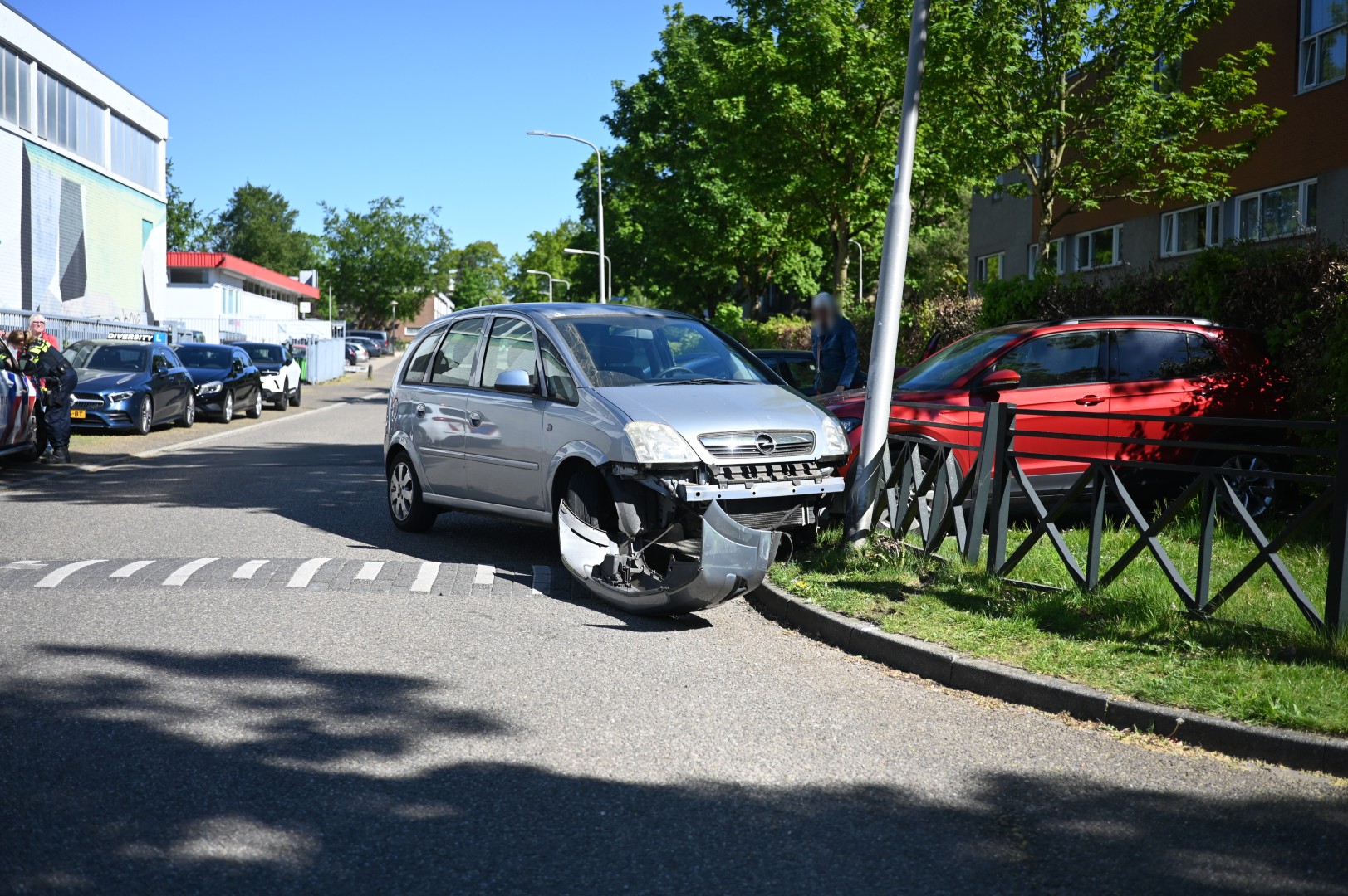 Automobiliste botst op geparkeerde auto en lantaarnpaal
