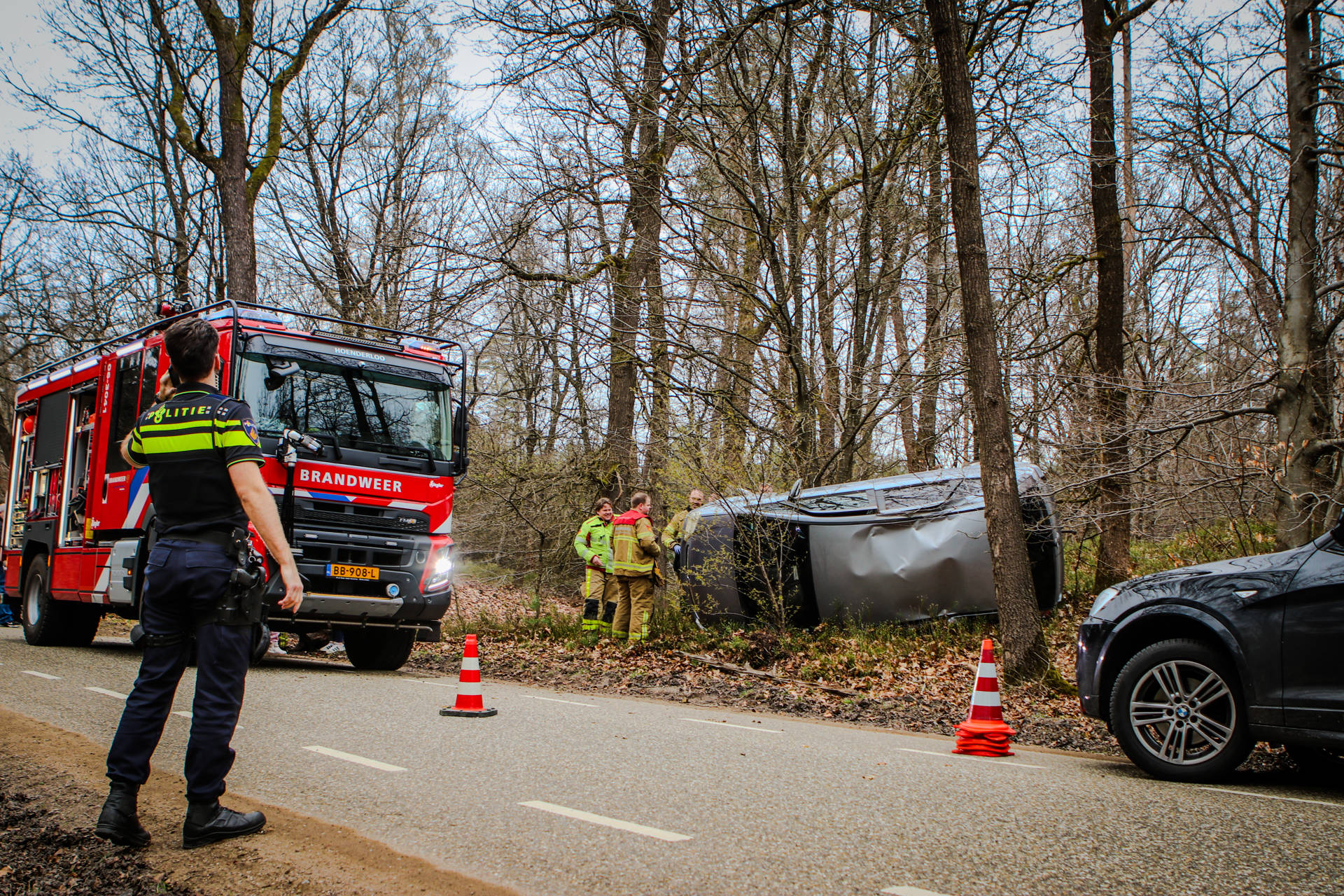 Auto belandt op zijkant tussen bomen