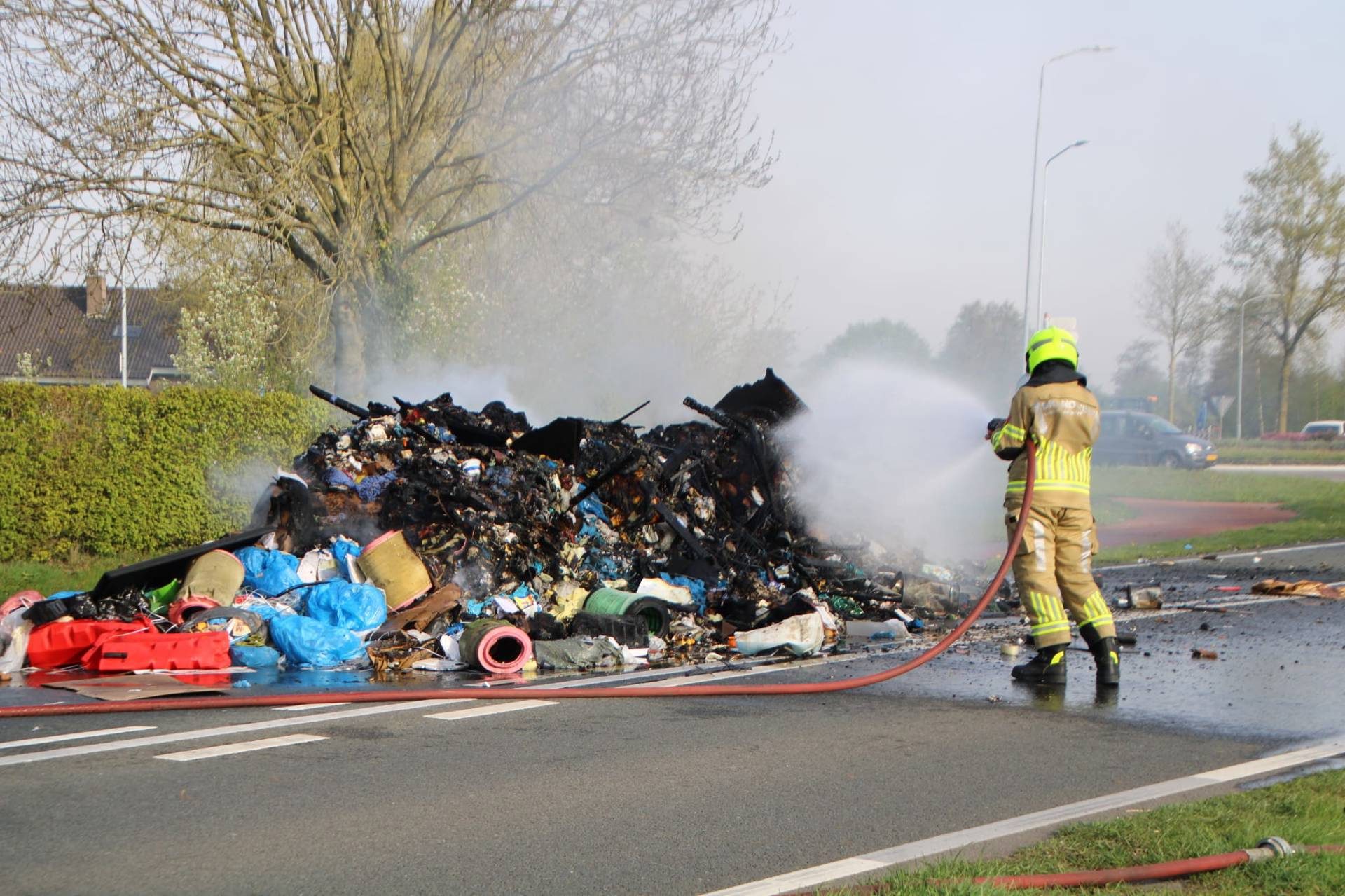 Vuilniswagen dumpt brandend afval midden op straat
