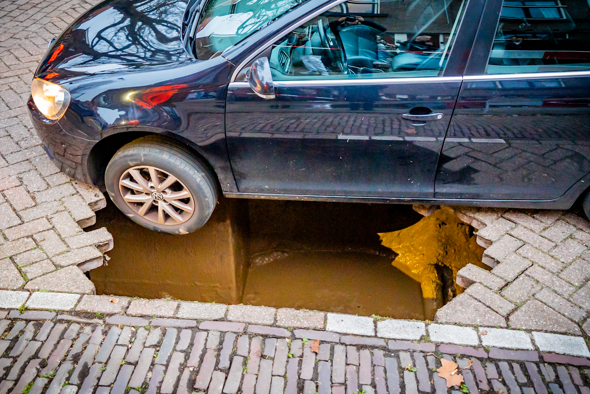 Auto belandt in sinkhole door verzakt wegdek